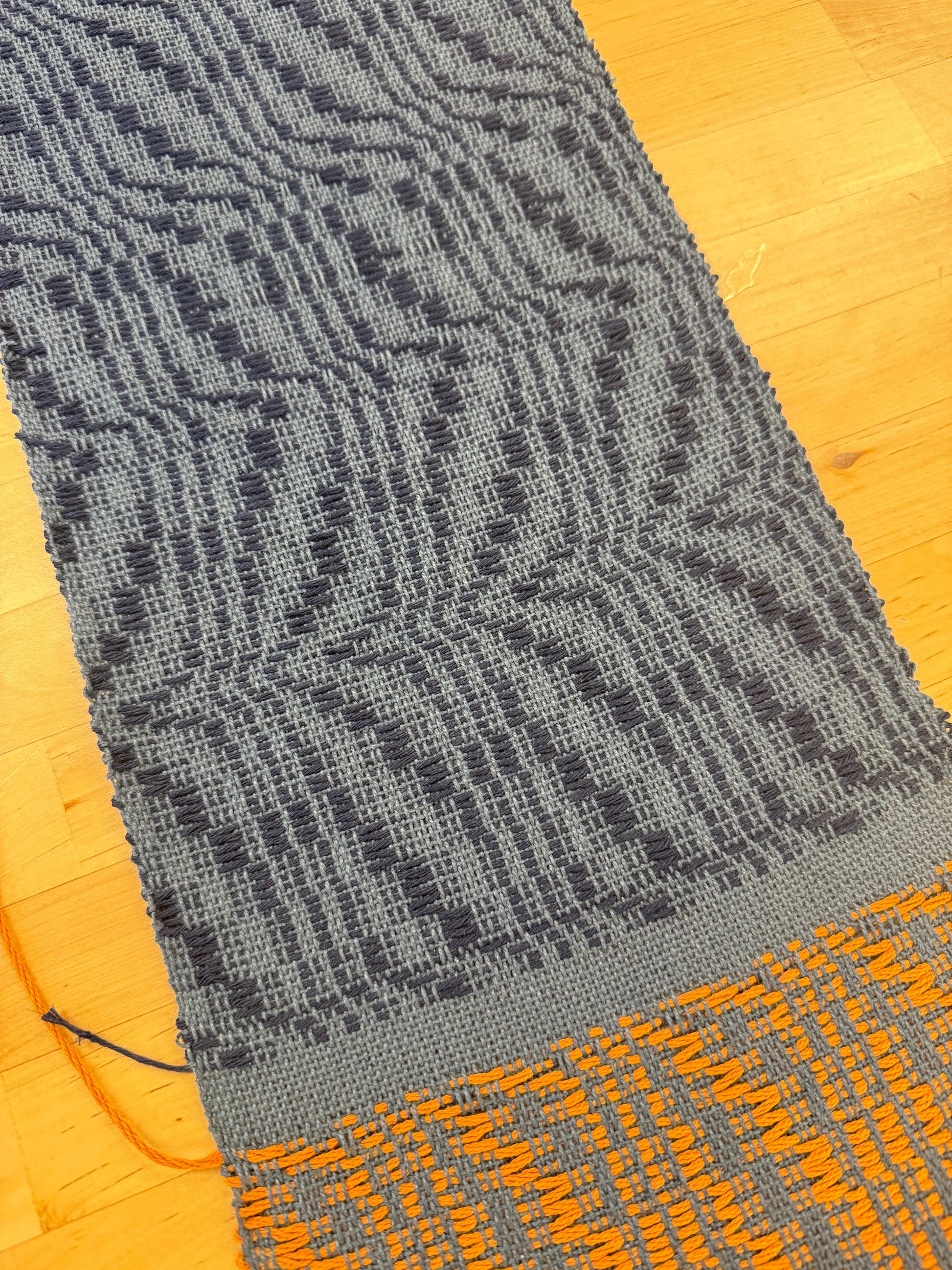Gray and orange textured fabric on a wooden surface